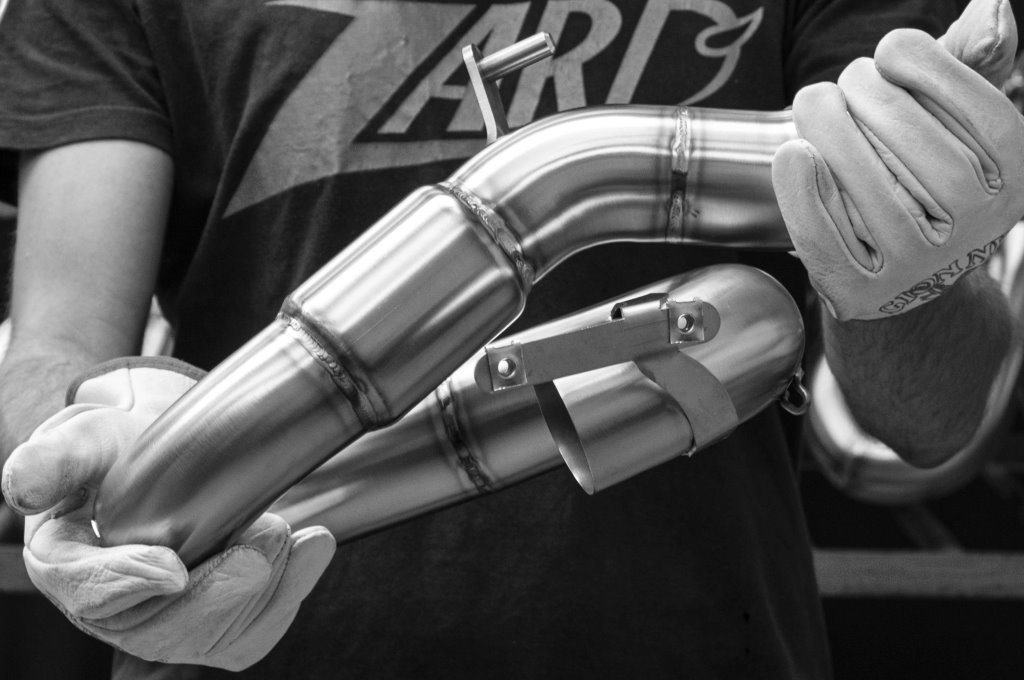 Ein Mitarbeiter von Zard hält eine Motorradauspuffanlage in den Händen.